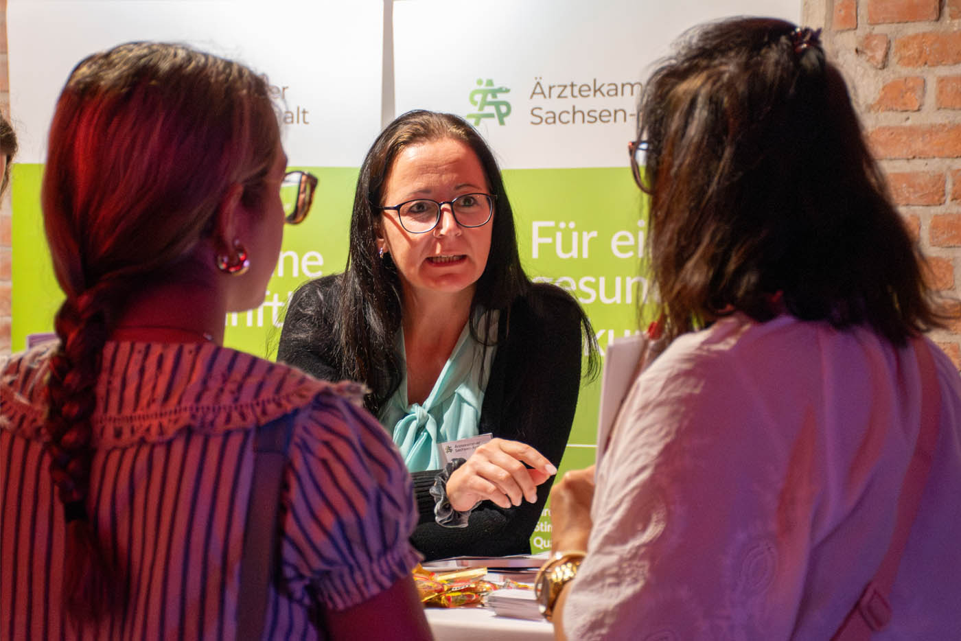 Frau unterhält sich mit zwei Frauen am Messestand