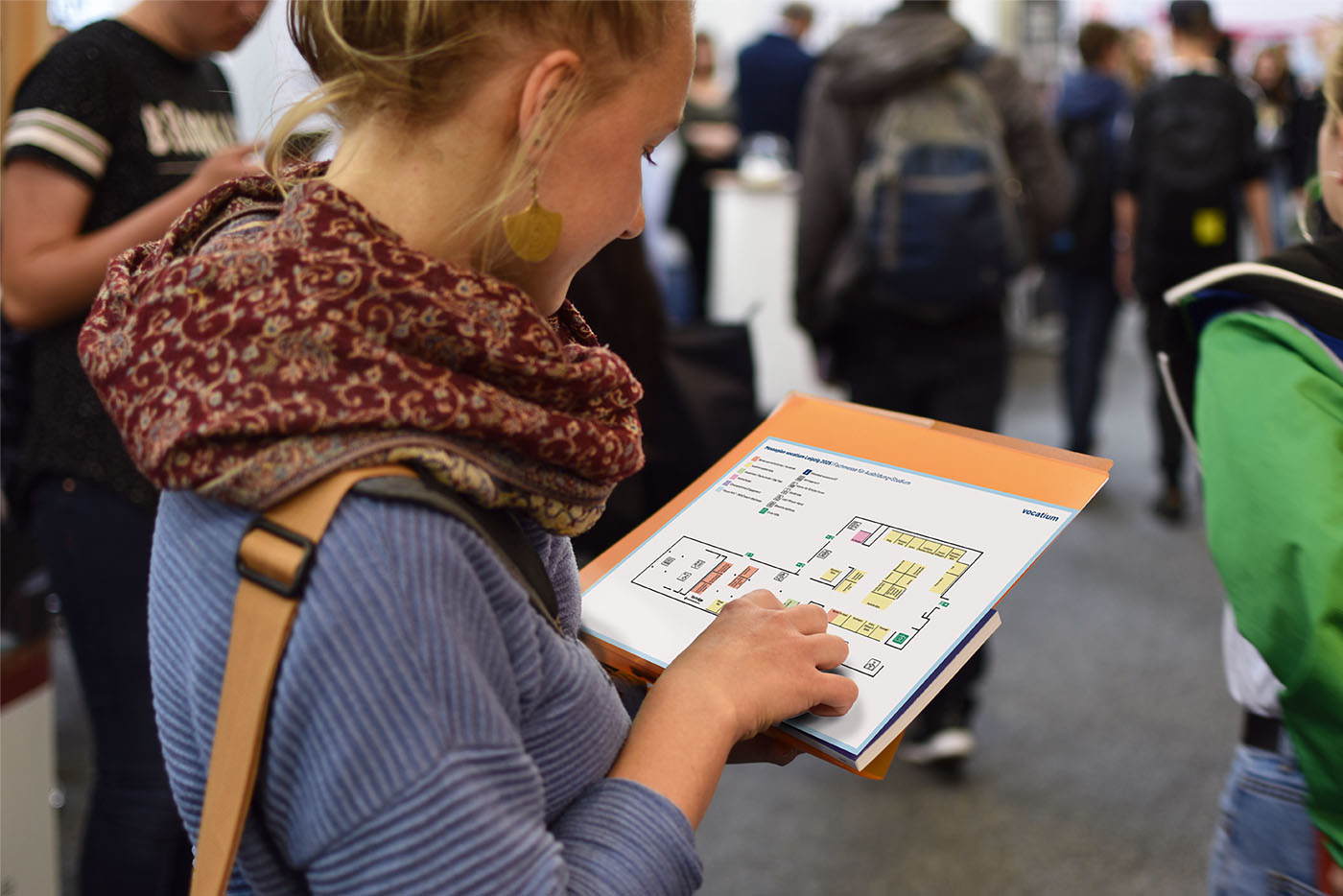 Frau schaut auf auf Messeplan, den sie in der Hand hält