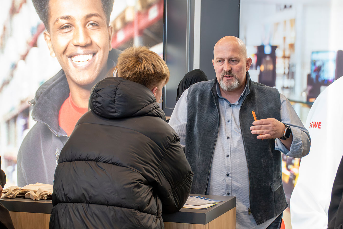 Mann in Weste unterhält sich mit jungen Mann