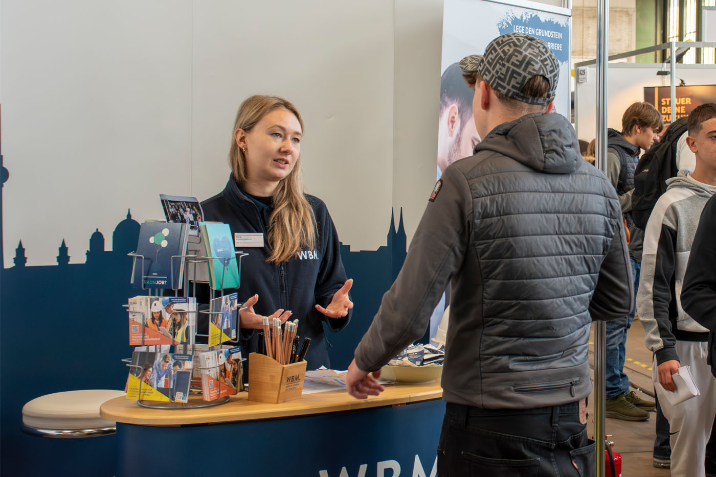 Frau unterhält sich am Messestand mit jungen Mann