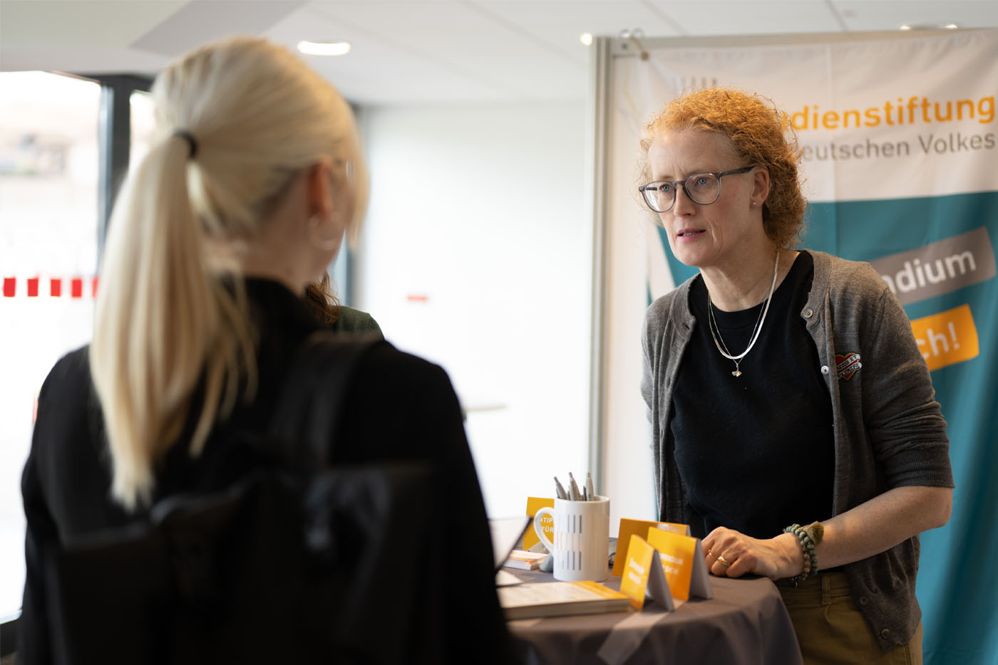 Frau unterhält sich mit junger Frau am Messestand